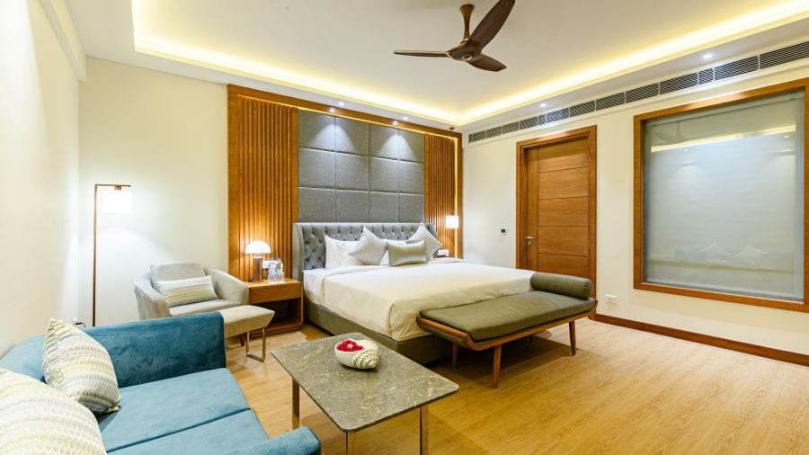 Nội thất phòng ngủ tại biệt thự tổng thống ở Ananta Resort Pushkar với giường, ghế sofa màu xanh và đồ nội thất khác.