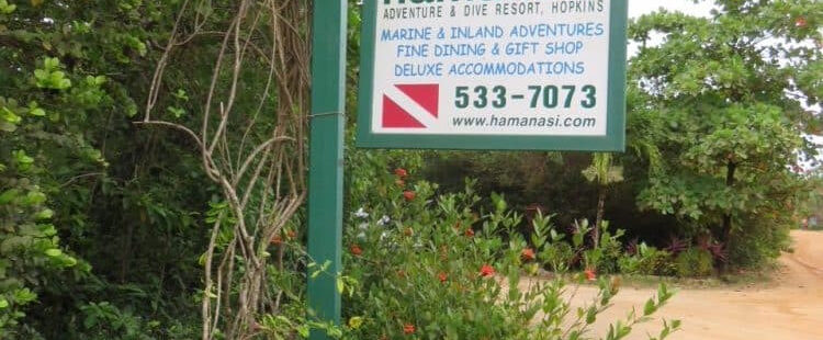 Lối vào khu nghỉ dưỡng Hamanasi Adventure and Dive Resort với biển hiệu mộc mạc