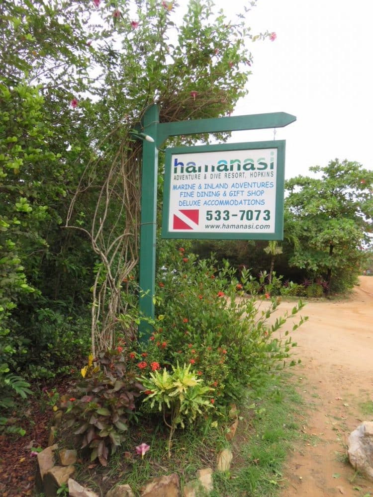 Lối vào khu nghỉ dưỡng Hamanasi Adventure and Dive Resort với biển hiệu mộc mạc