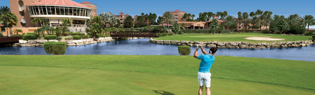 Sân golf tại Divi Village Golf & Beach Resort ở Aruba với thảm cỏ xanh mướt và hồ nước nhân tạo, tạo nên một không gian thư giãn và lý tưởng cho những người yêu thích golf.