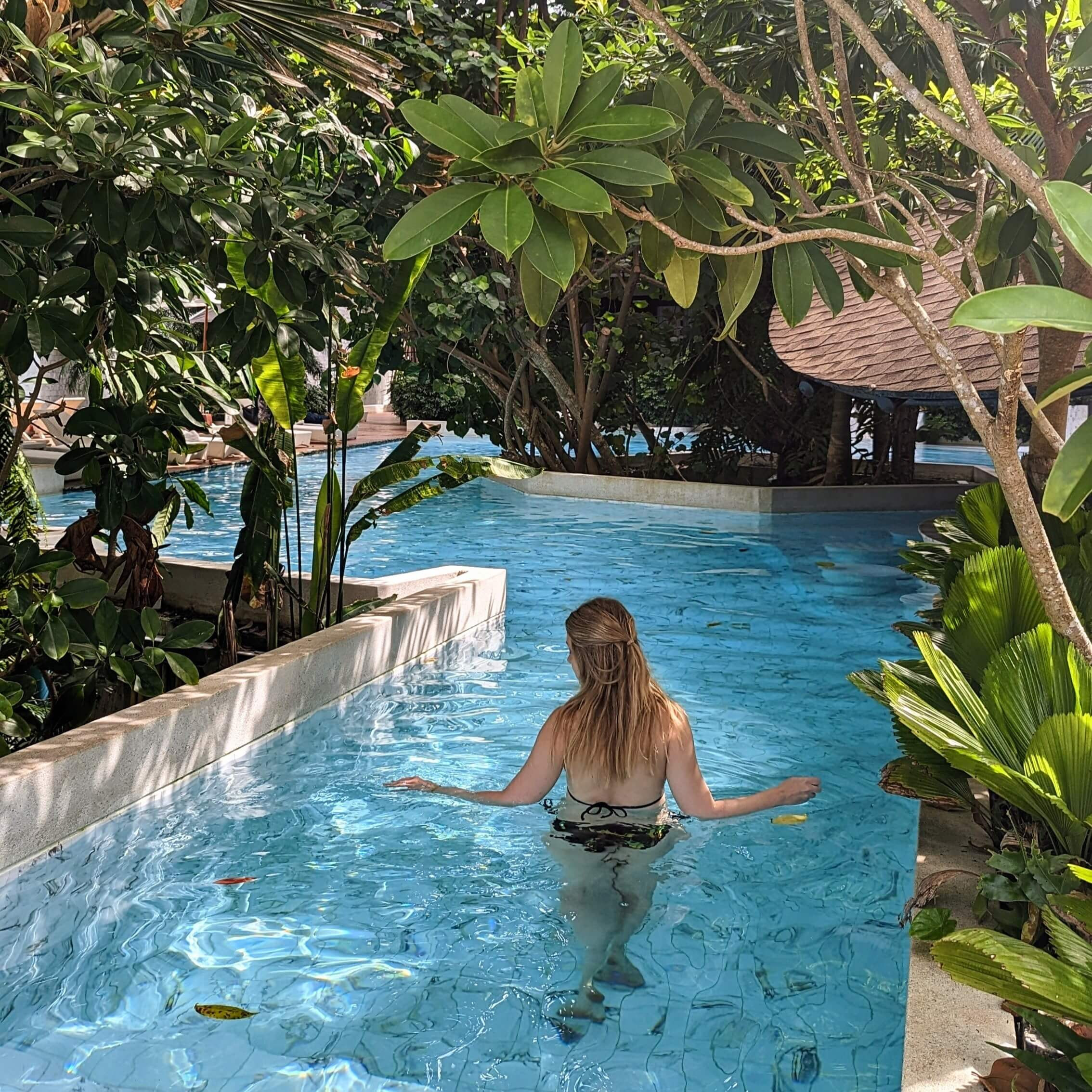Hồ bơi với lối đi bộ bao quanh bởi cây xanh tại Panan Krabi Resort